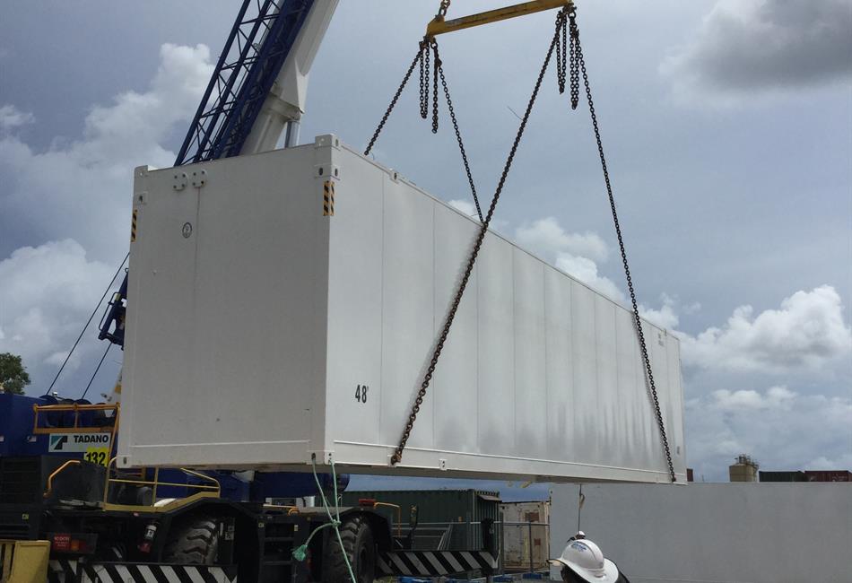 a large white shipping container is being lifted by a crane .