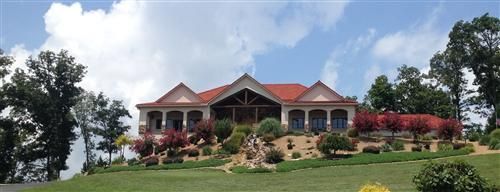 A large house with a red roof is surrounded by trees