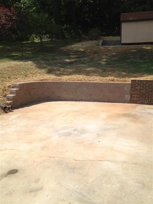 A concrete driveway with a brick wall and stairs in the background.