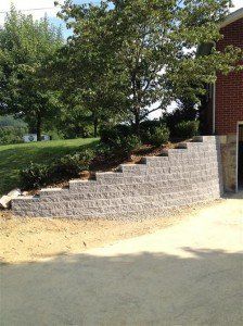 A brick wall is being built in front of a brick house.