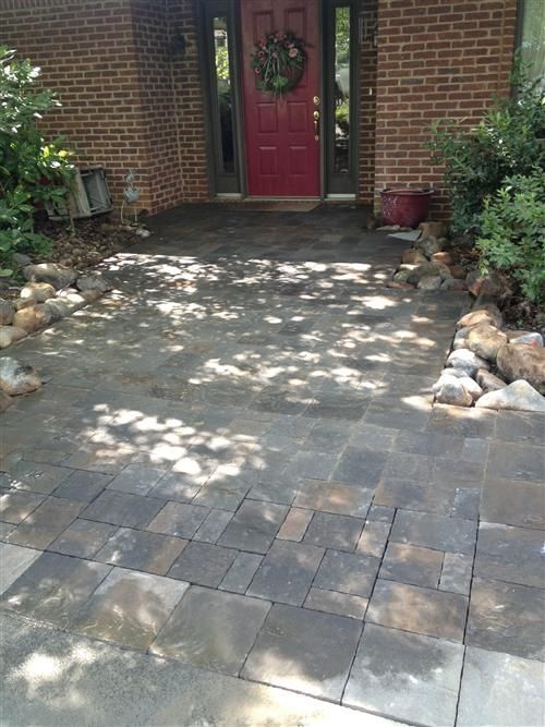 A brick house with a red door and a patio in front of it