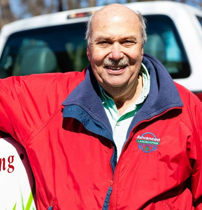 A man wearing a red jacket that says automotive on it