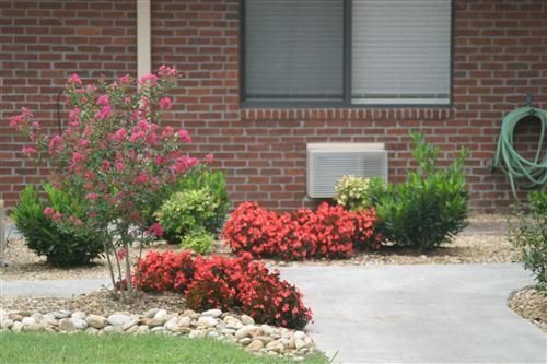 A brick building with a hose and flowers in front of it