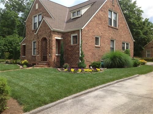 A large brick house with a lush green lawn in front of it
