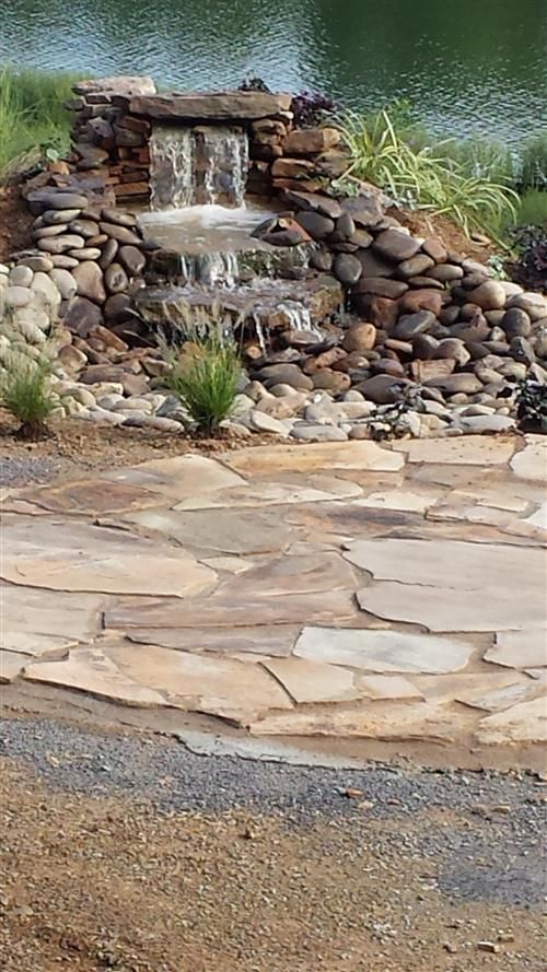 There is a waterfall in the middle of a stone patio.
