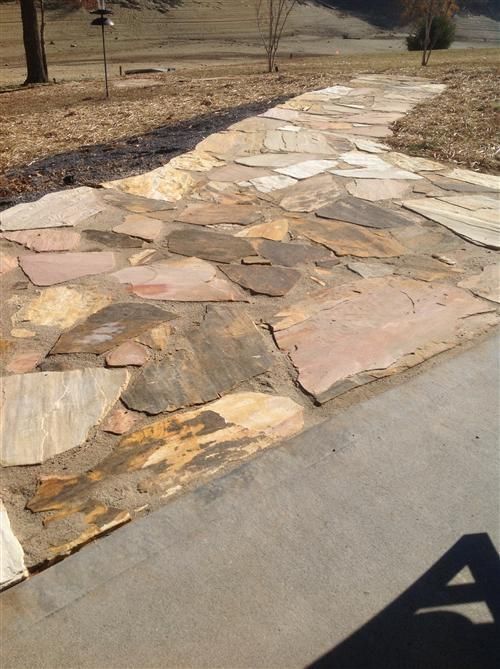 A stone walkway leading to a concrete driveway.
