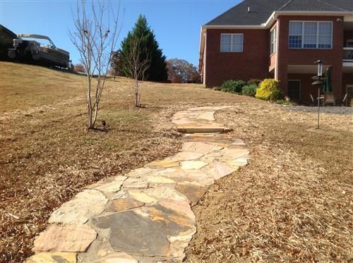 A stone walkway leads to a large brick house