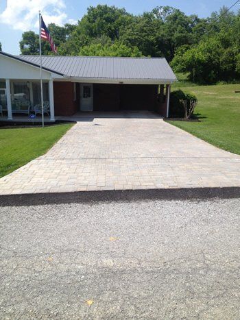 A driveway leading to a house with an american flag in the background.