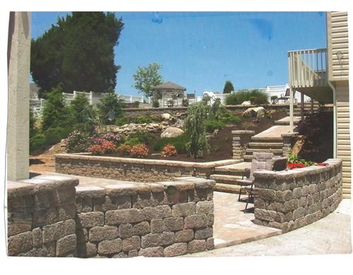 A picture of a backyard with a stone wall and stairs