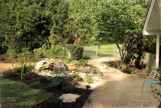 A lush green garden with a waterfall in the middle of it
