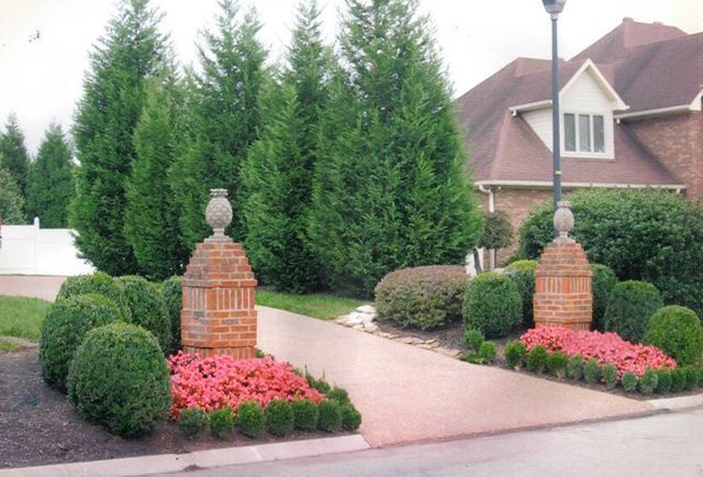 A brick entrance to a house with flowers and bushes