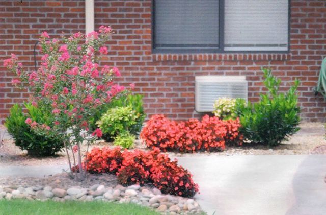 A brick house with flowers in front of it and a window.