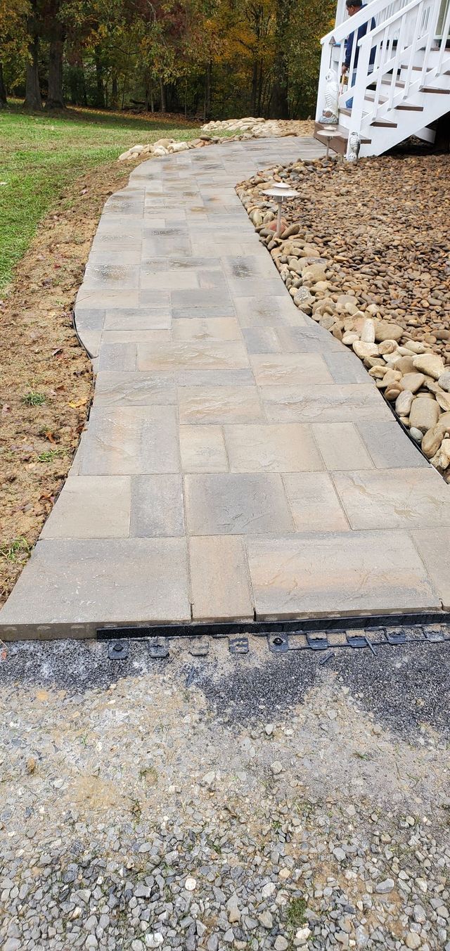 A stone walkway leading to a white deck in a yard.