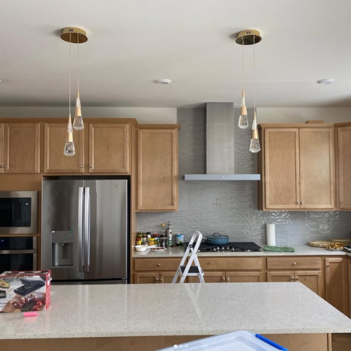 Kitchen with light wood cabinets, stainless steel appliances, and two pendant lights above the island.