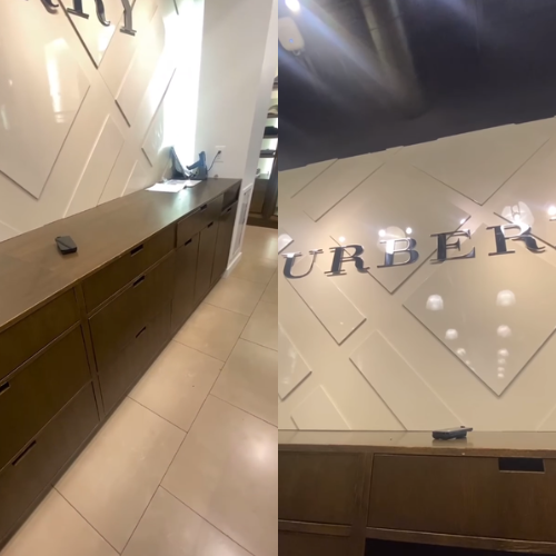 Interior of a Burberry store with a counter and logo on the wall. Beige and brown tones.