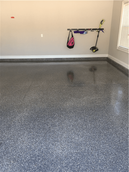 Finished garage floor with speckles, reflective, gray. Walls are beige, with a few items hanging.