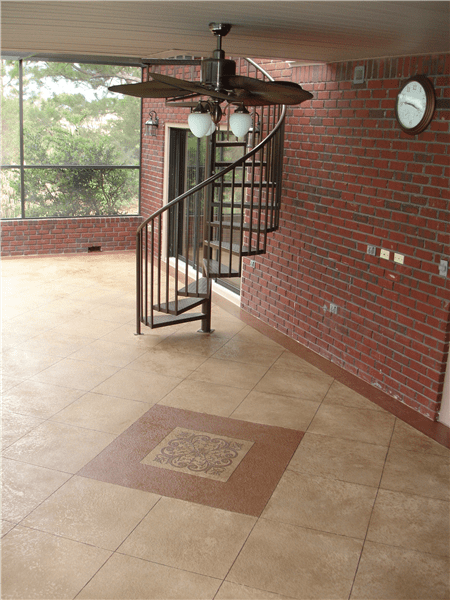 Indoor patio with a spiral staircase, brick walls, and tile floor, a ceiling fan, and a view of trees.