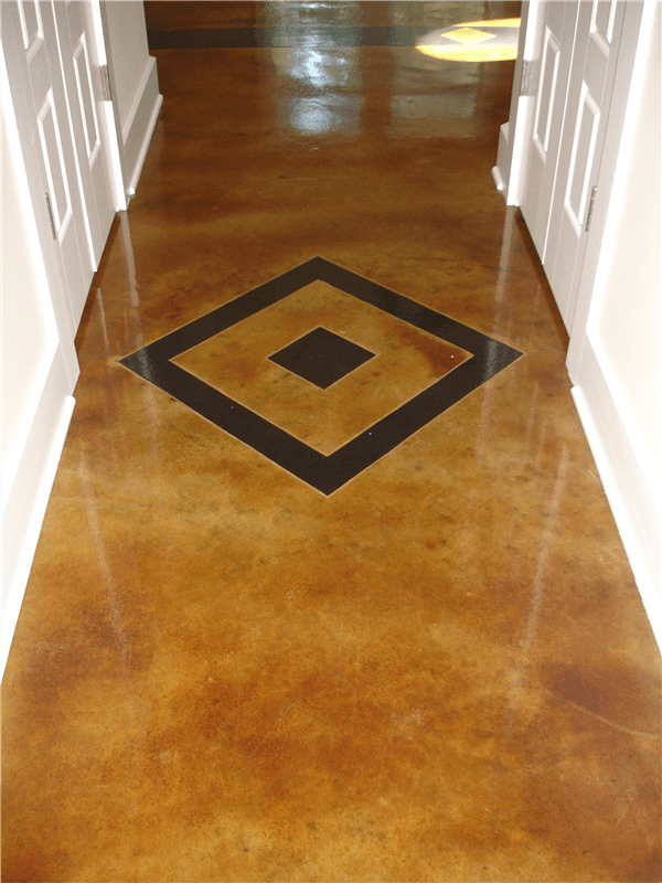 Brown, stained concrete hallway with a decorative diamond design in darker brown. White door frames.