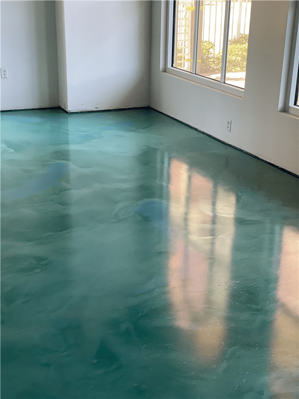 Green epoxy floor in a room, reflecting sunlight from windows.