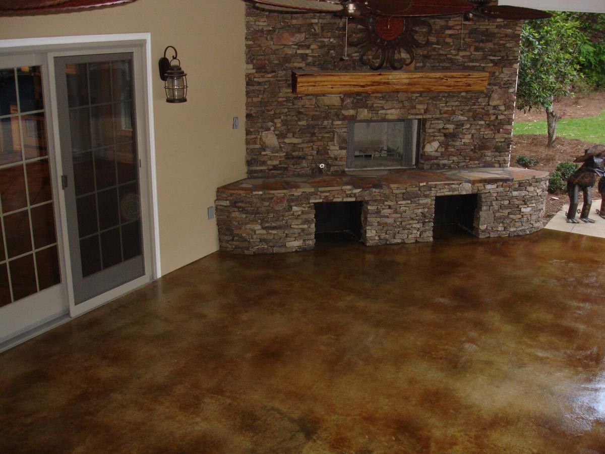 Outdoor patio with stained concrete floor, stone fireplace, and sliding glass door.