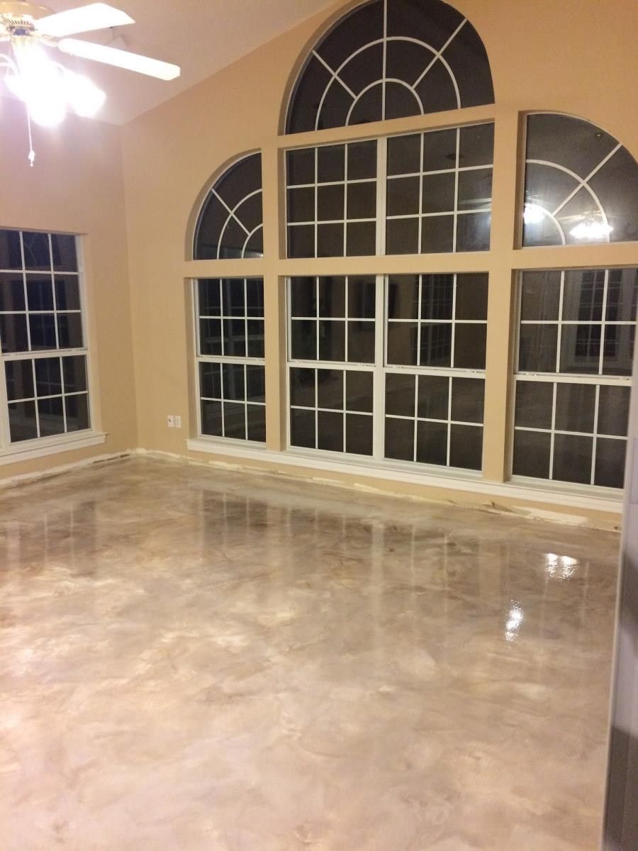 Large room with shiny, metallic-looking floor and large windows with arched tops.