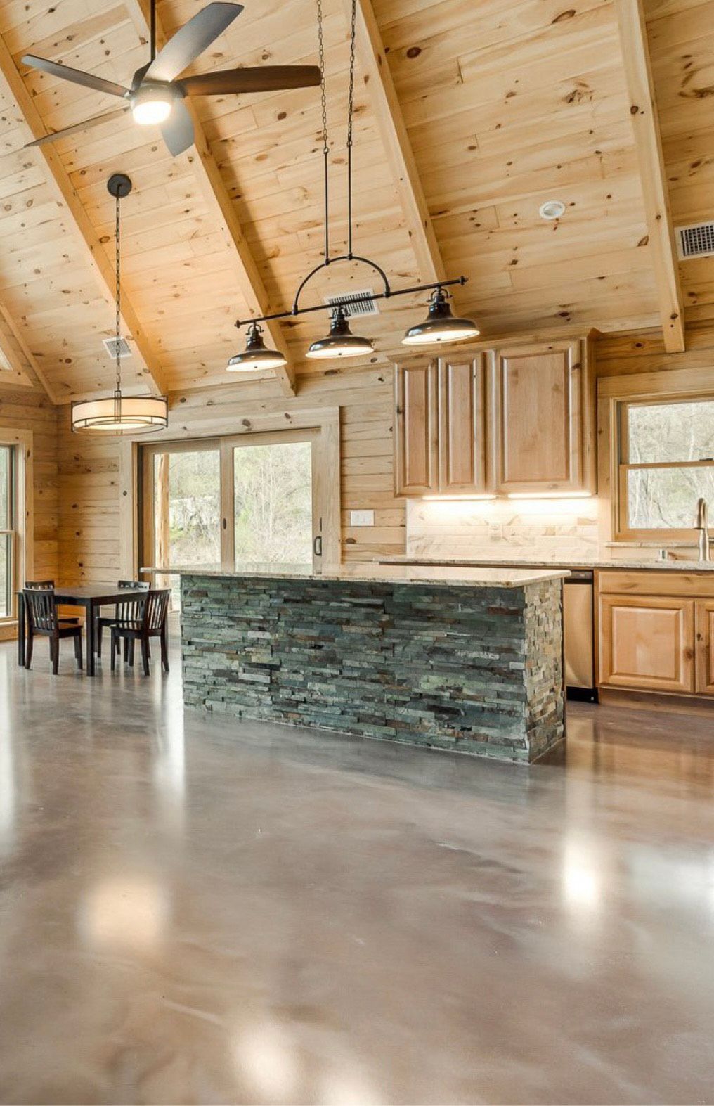 Kitchen with stone island, wooden cabinets, and ceiling. Polished concrete floor.