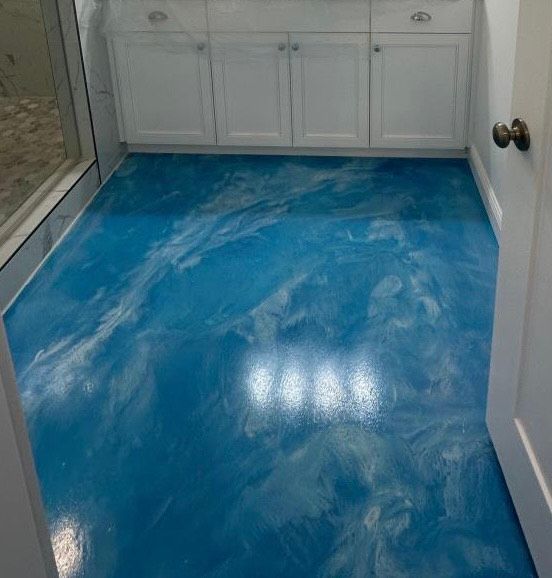 Blue and white epoxy bathroom floor with white cabinets.