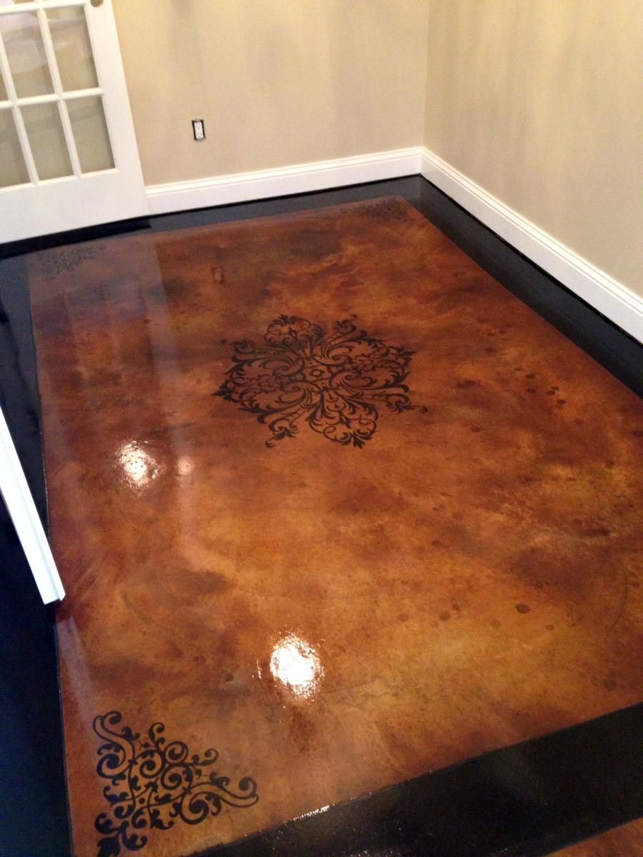 Brown and black stained concrete floor with ornate black floral stencil design, in a room with white trim.
