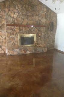 Fireplace with stone facade, gold trim, wooden mantel, on shiny brown floor.
