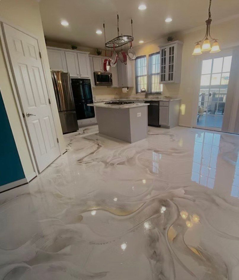 Kitchen with shiny, marbled epoxy floor, white cabinets, and island. Natural light floods the space.