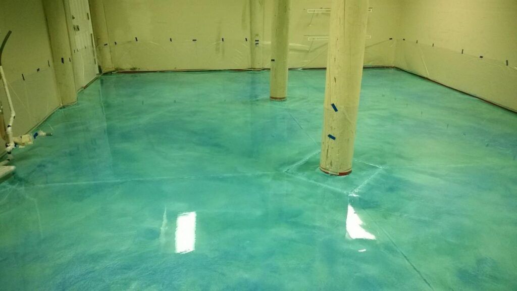 Blue and green epoxy floor in a room with white columns and walls.