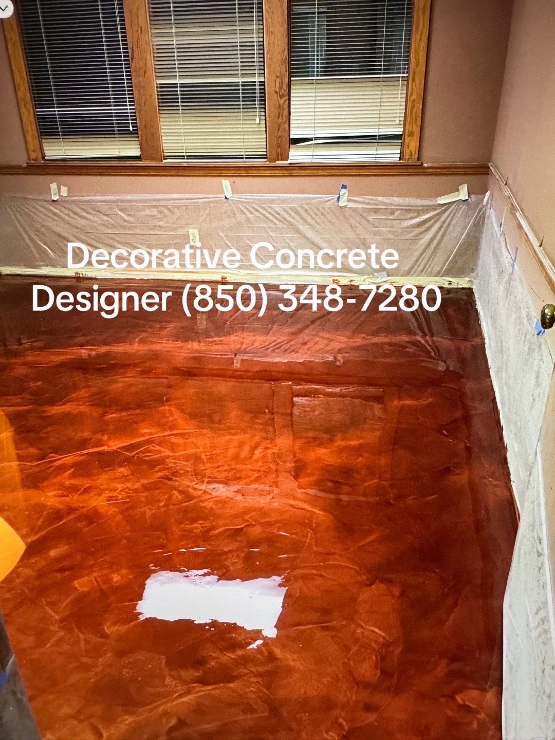 Metallic orange epoxy concrete floor in a room, with protective sheeting overhead.