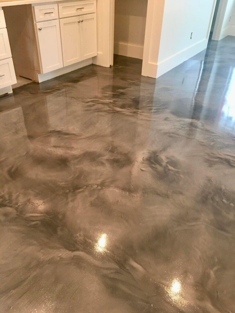 Shiny metallic epoxy floor in a room with white cabinets.