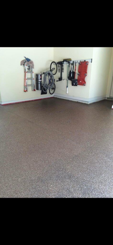 Garage interior with tools and a bicycle hanging on the wall. Speckled floor, beige walls.