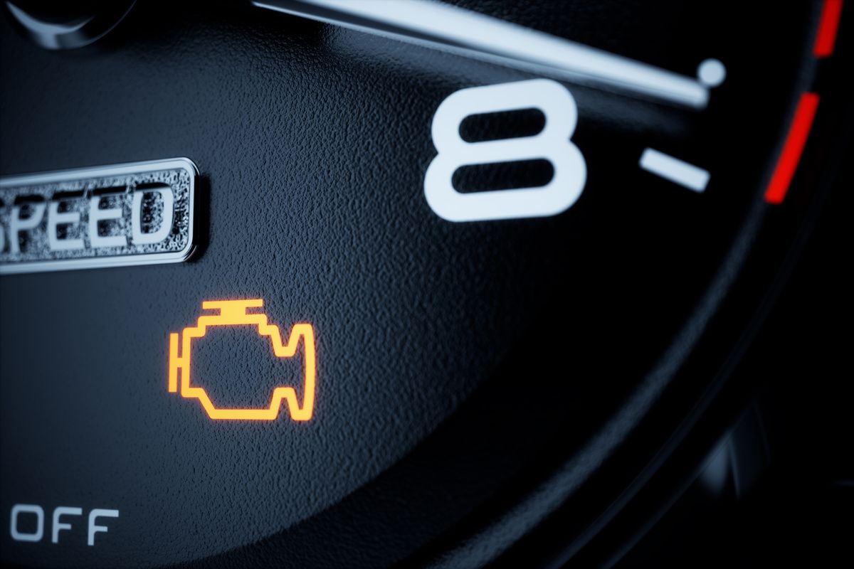 A yellow check engine light symbol illuminated on a vehicle's dark dashboard gauge cluster.