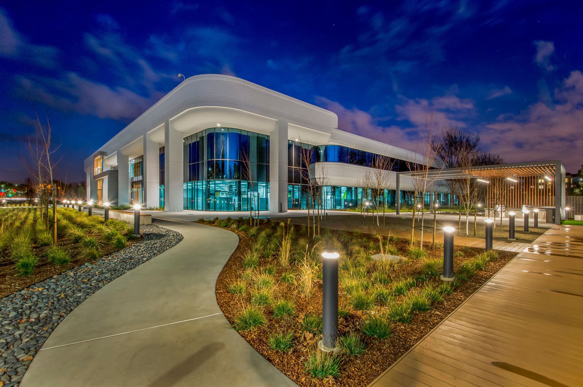 Modern commercial building with architectural bollard lighting along curved walkway at night