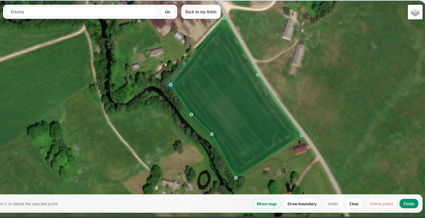 Satellite view of green farmland with fields, hedgerows, and a winding road for field selection in the SoilyWorld Platform