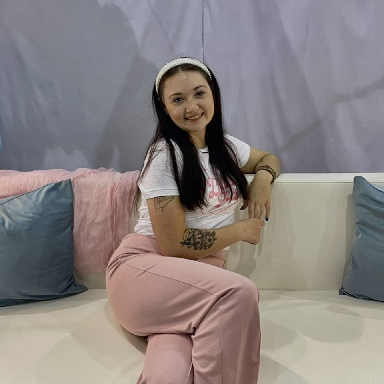 A woman in a blue shirt is taking a selfie in front of an alphabet poster.