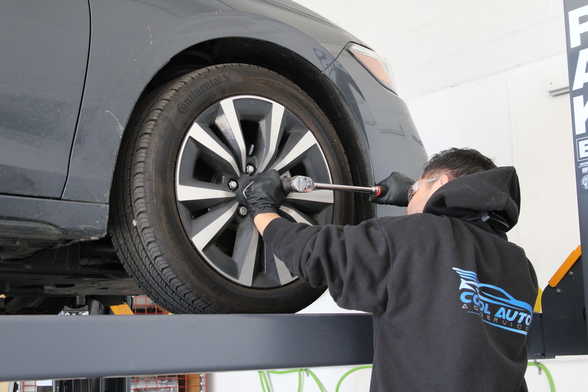 A man is changing a tire on a car on a lift.