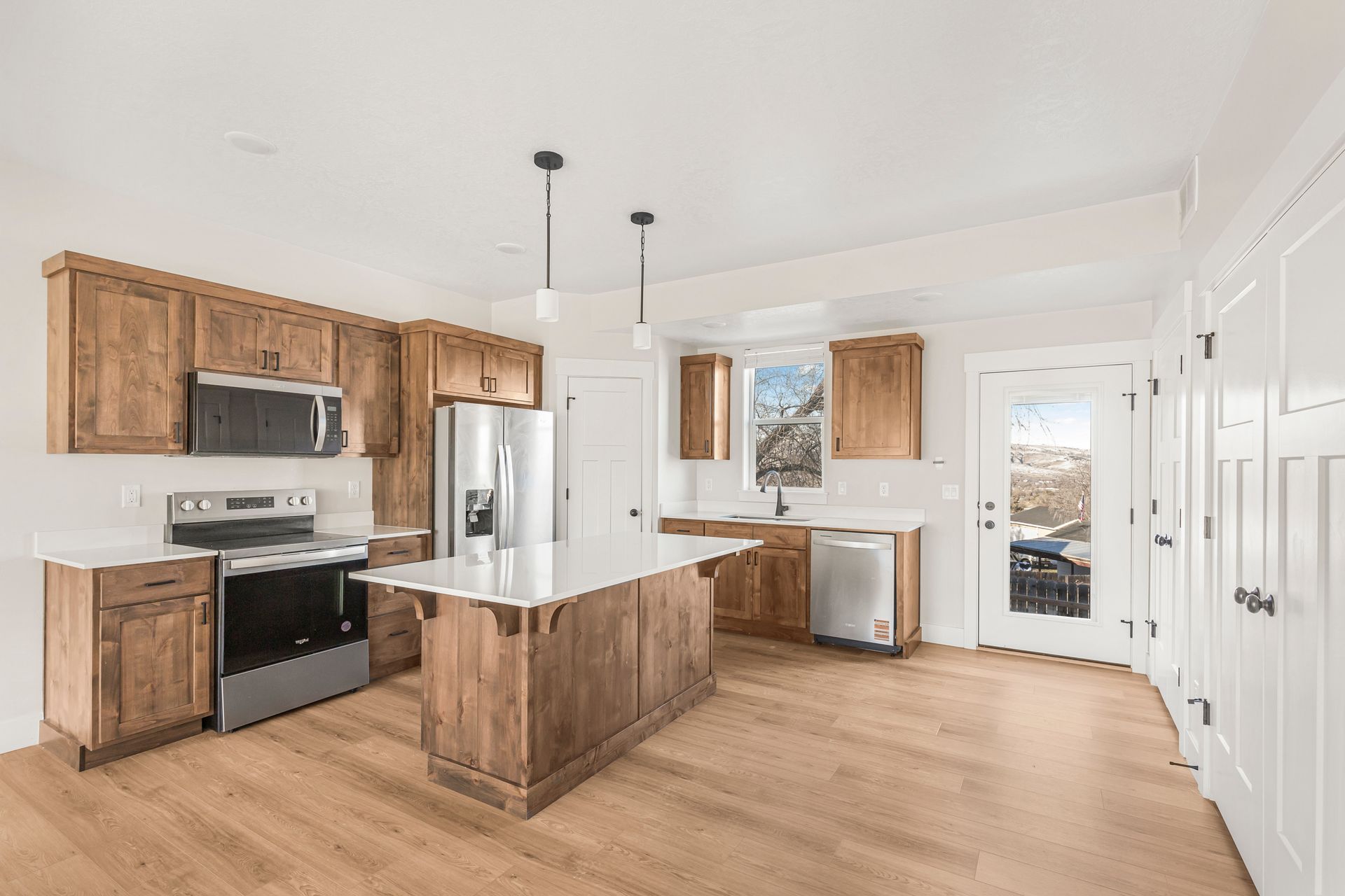 Kitchen with wood cabinets, stainless steel appliances, white countertops, and an island.