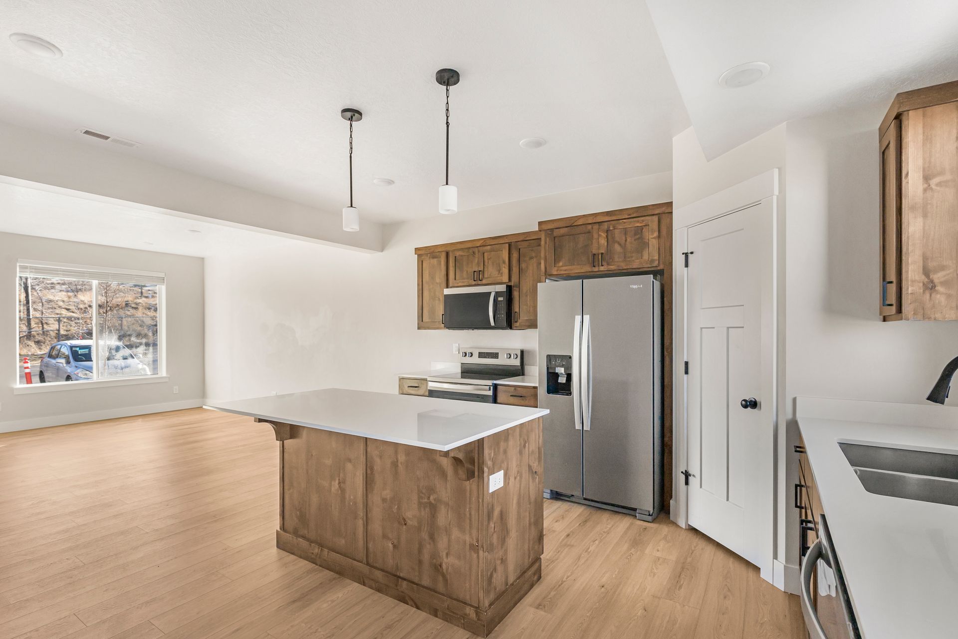 Kitchen with light wood cabinets, stainless steel appliances, and a white countertop island.