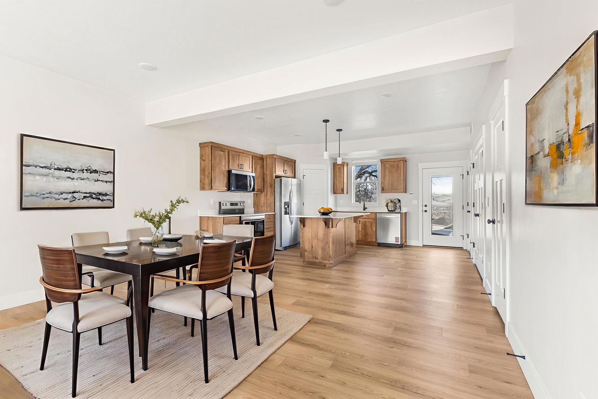 Dining room with table and chairs, connected to a kitchen with wooden cabinets and stainless steel appliances.