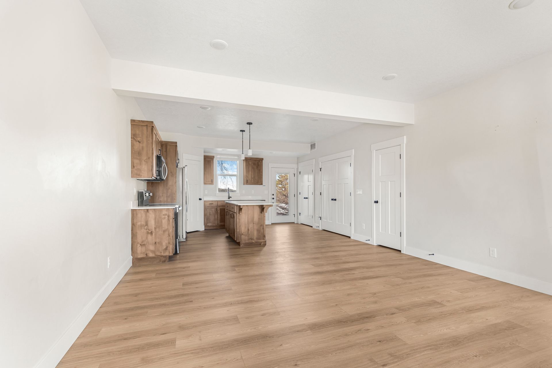 Open-concept kitchen and living area with wood cabinets, island, and light wood flooring.