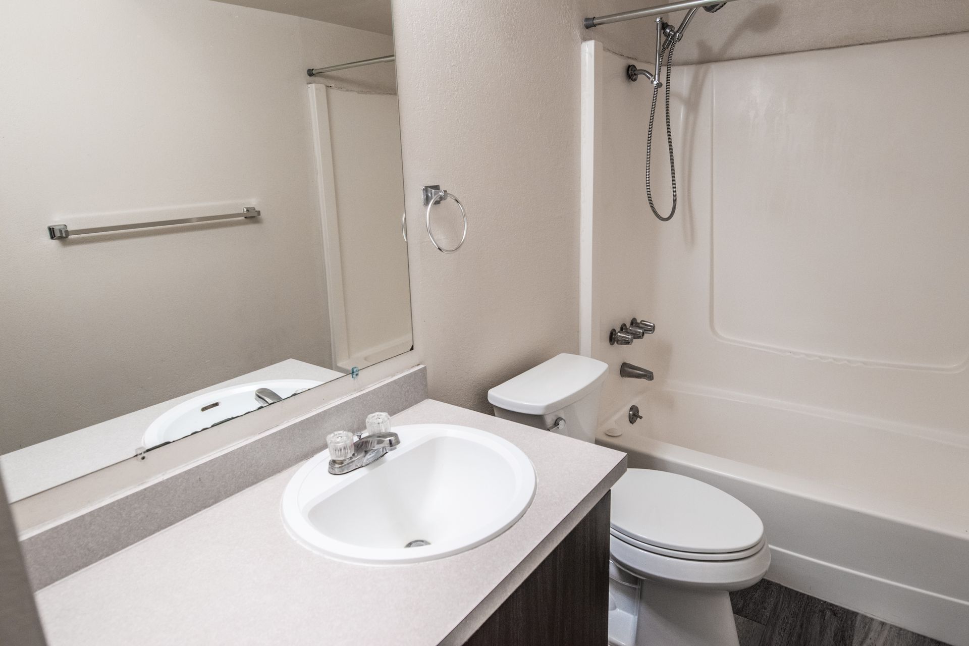 Bathroom with a white sink, toilet, and bathtub. Light gray countertop, silver fixtures, and tan walls.