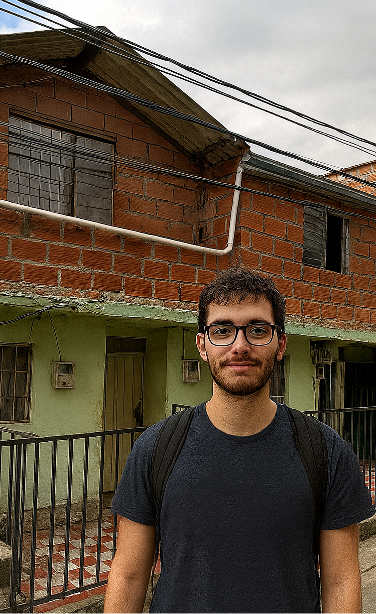 Man with glasses and backpack in front of a red brick house with green accents; cloudy sky.