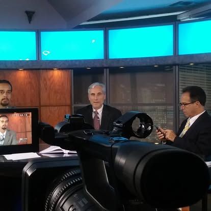 A group of men are sitting in front of a camera