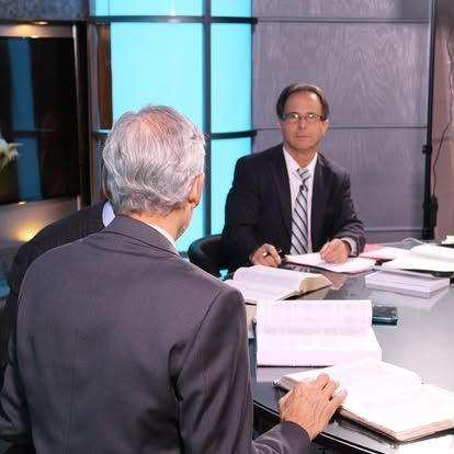 Two men are sitting at a table reading books