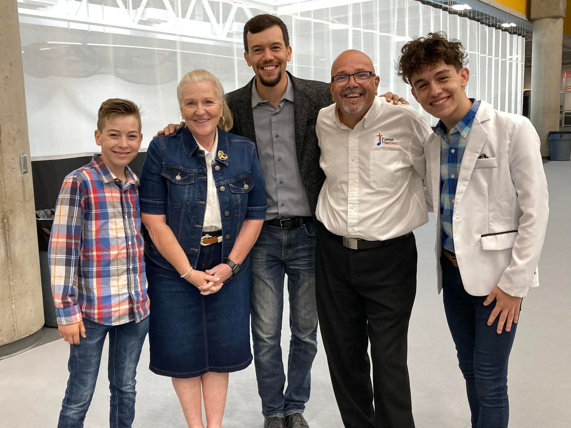 Woman with arms raised in a crowd, likely at a concert or church service with stage lights in the background.