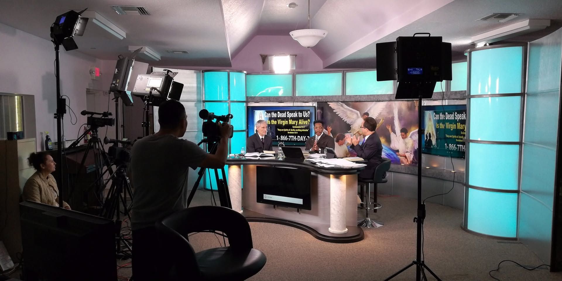 A man is holding a camera in a news studio