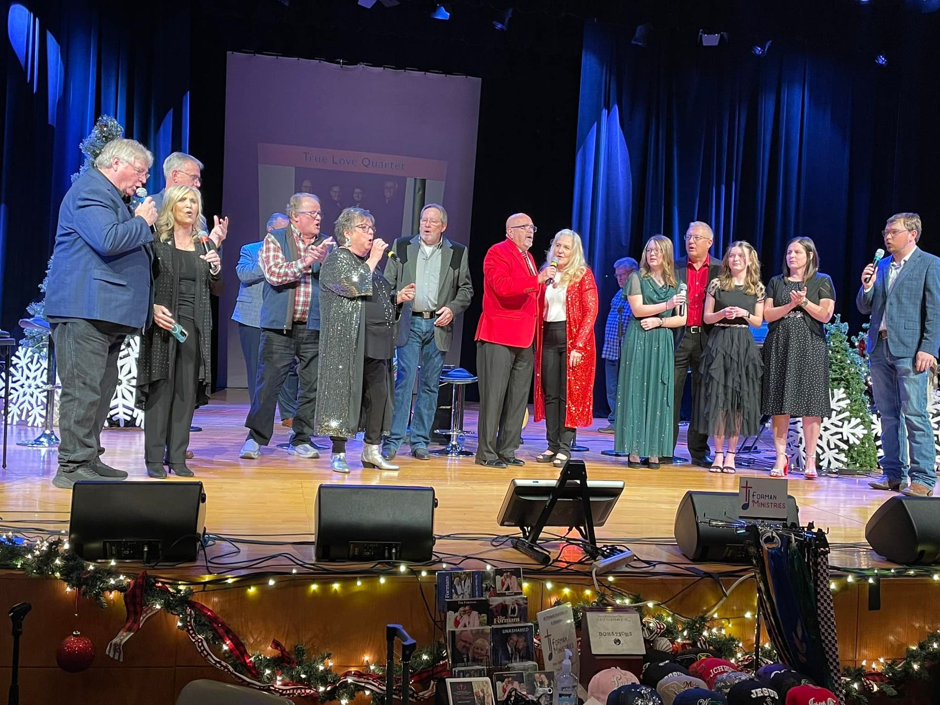 A group of people on stage, microphones in hand, appear to be taking a bow.
